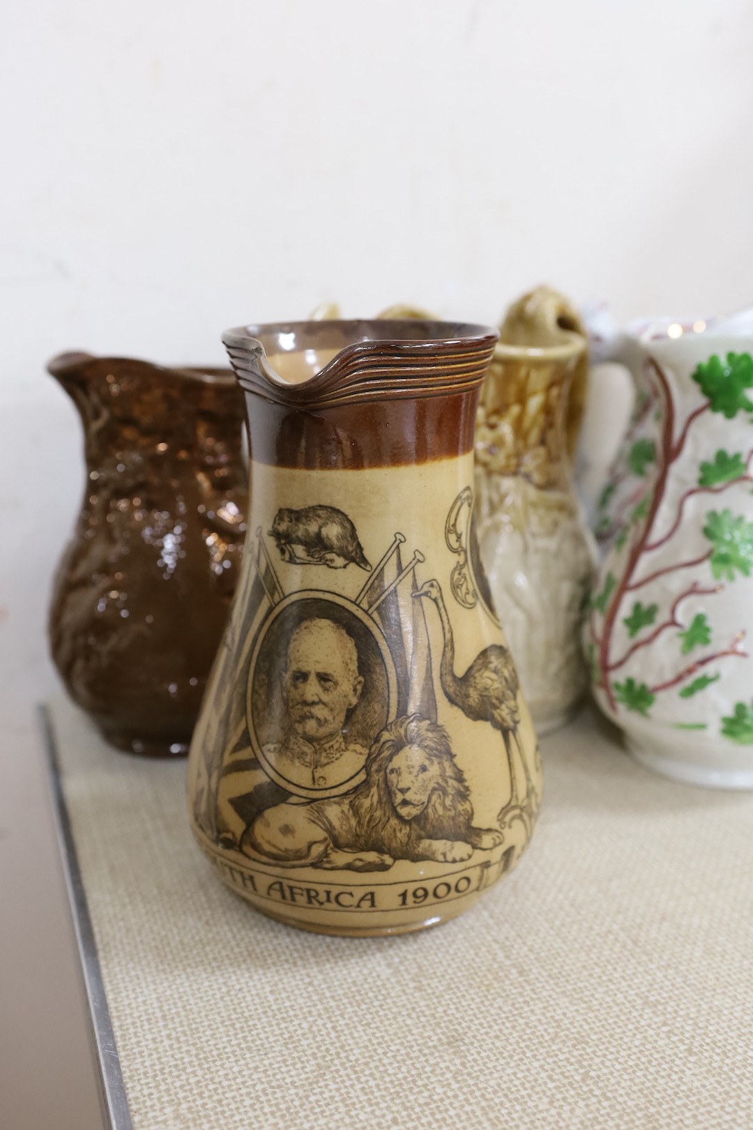 A Doulton Lambeth South Africa 1900 commemorative jug, 21cm, two relief moulded Volunteer jugs and four other jugs